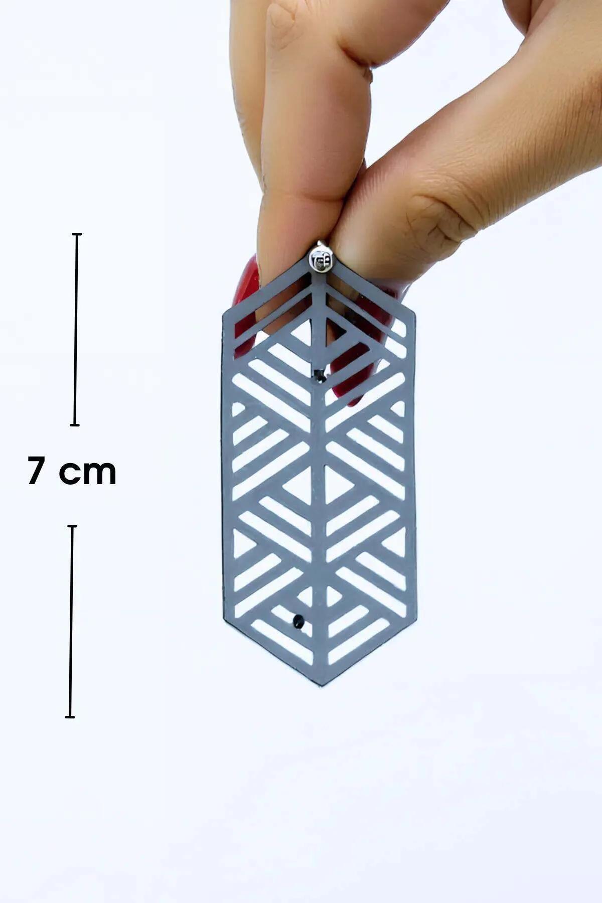 Reflektörlü beyaz geometrik küpe karanlık fon önünde parlayan yüzey detayı
