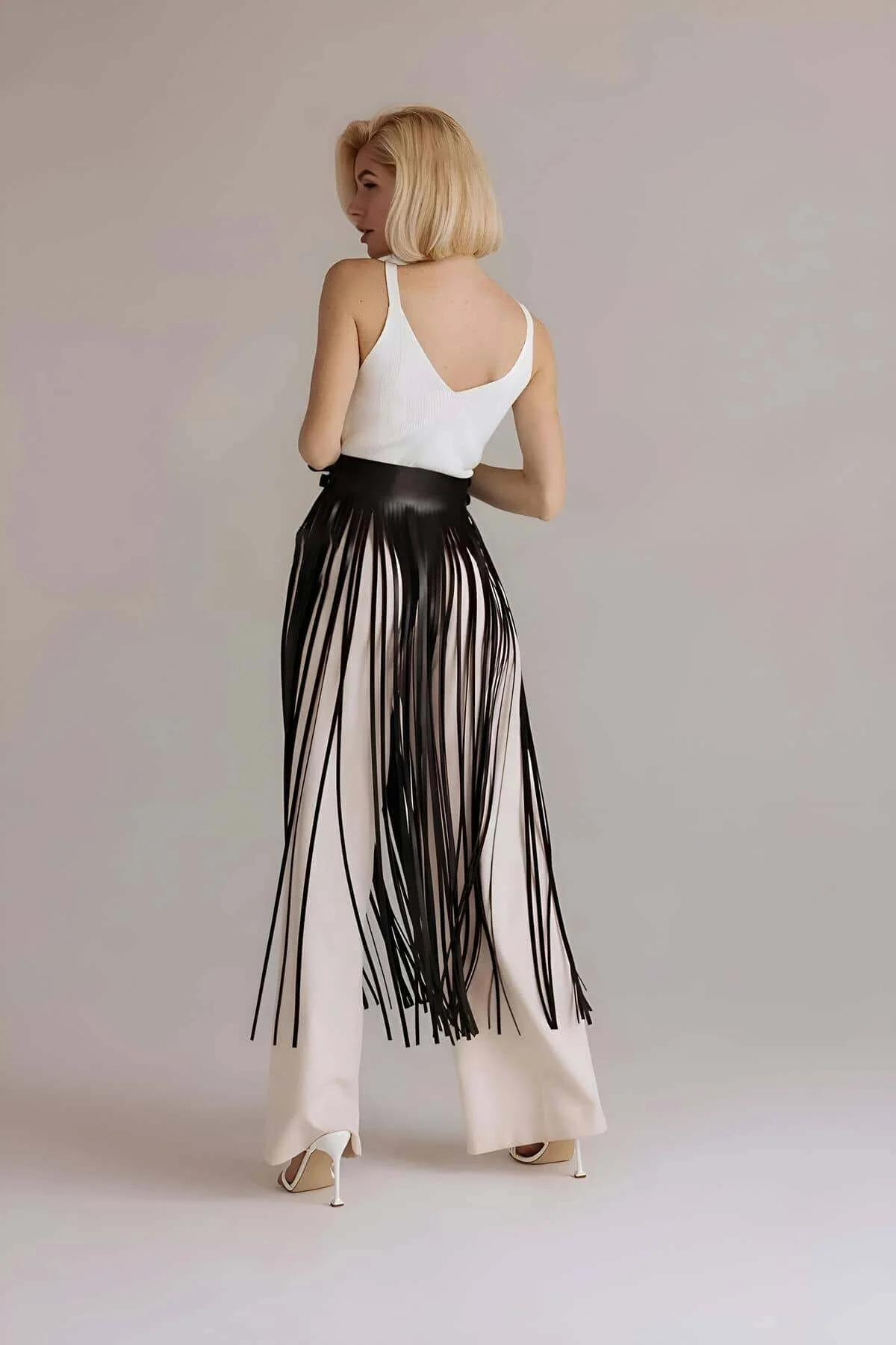 Black faux leather fringe strands cascading from structured belt waistband, fluid movement detail