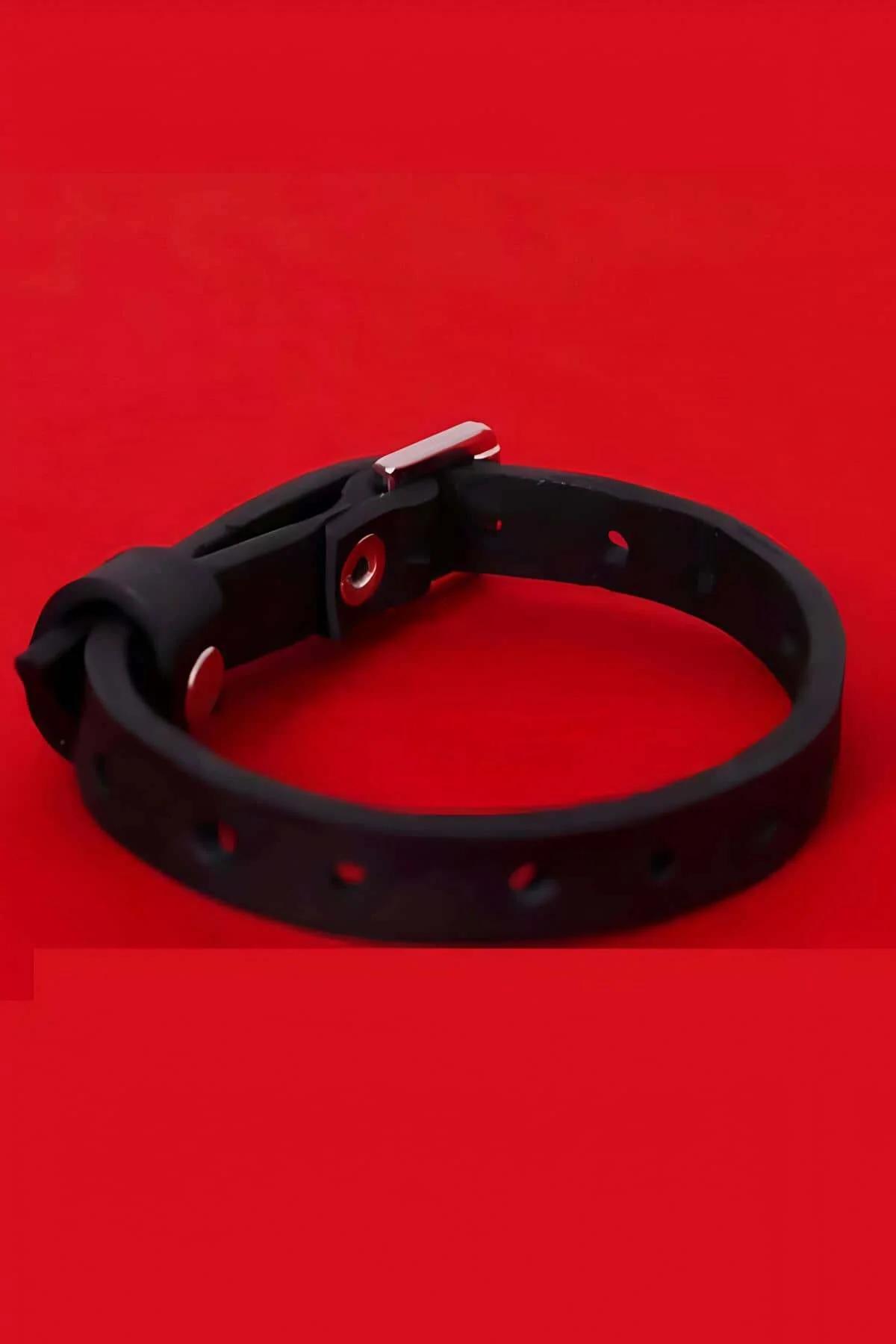Close-up of rectangular gold-tone metal buckle on black faux leather bracelet strap
