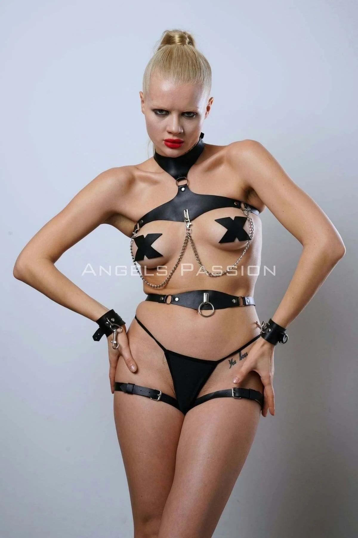 Close-up of silver chain drape connecting black faux leather chest harness frame to waist O-ring belt