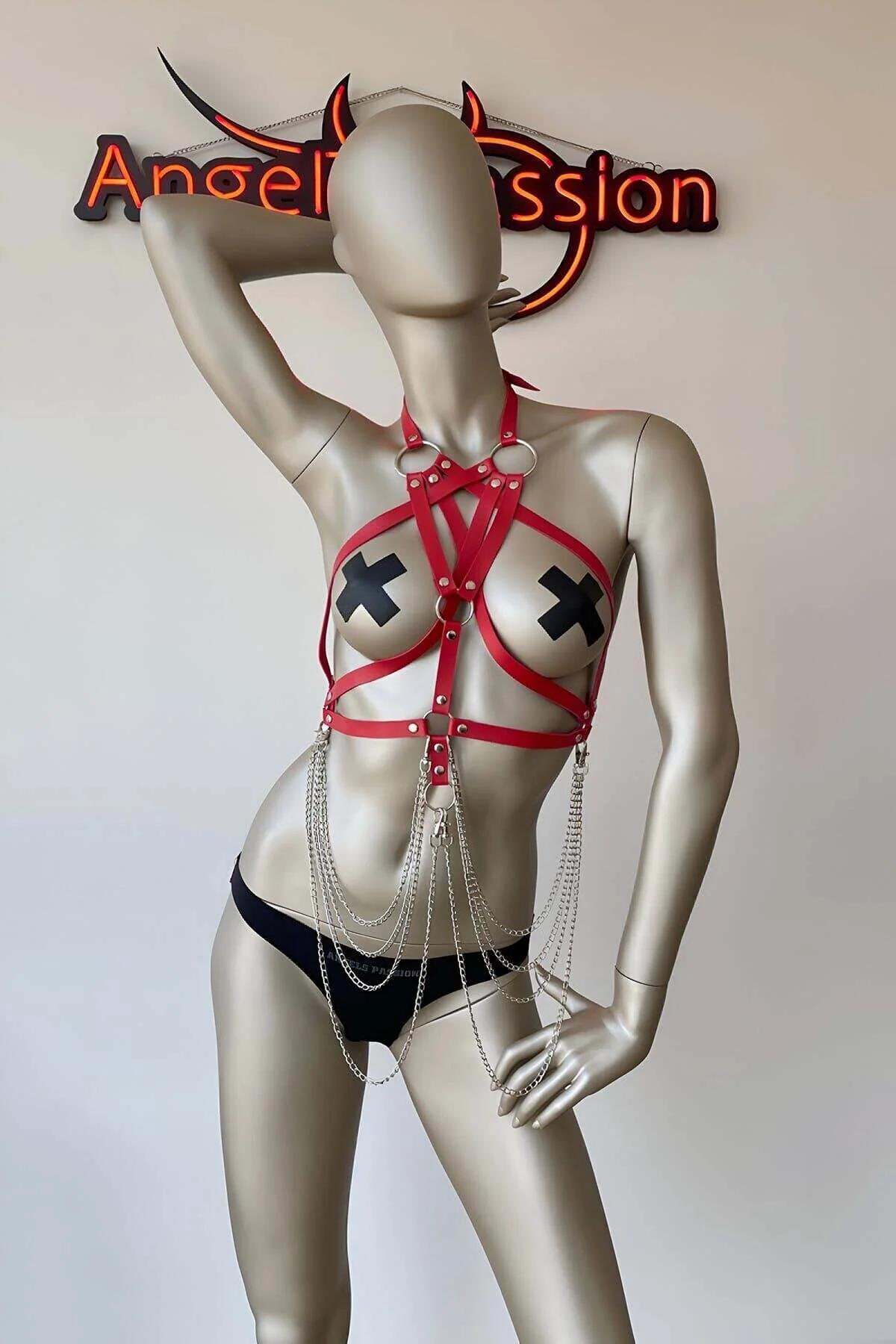 Close-up of silver O-ring and stud rivets on red faux leather chest harness straps