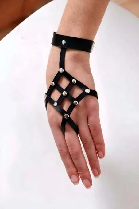 Black faux leather studded grid hand harness with wide wrist cuff and silver dome studs over back of hand