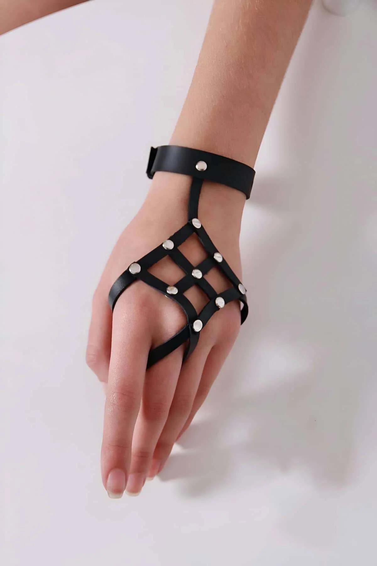 Studded black PU leather hand harness worn over bare skin showing nine silver dome stud intersections