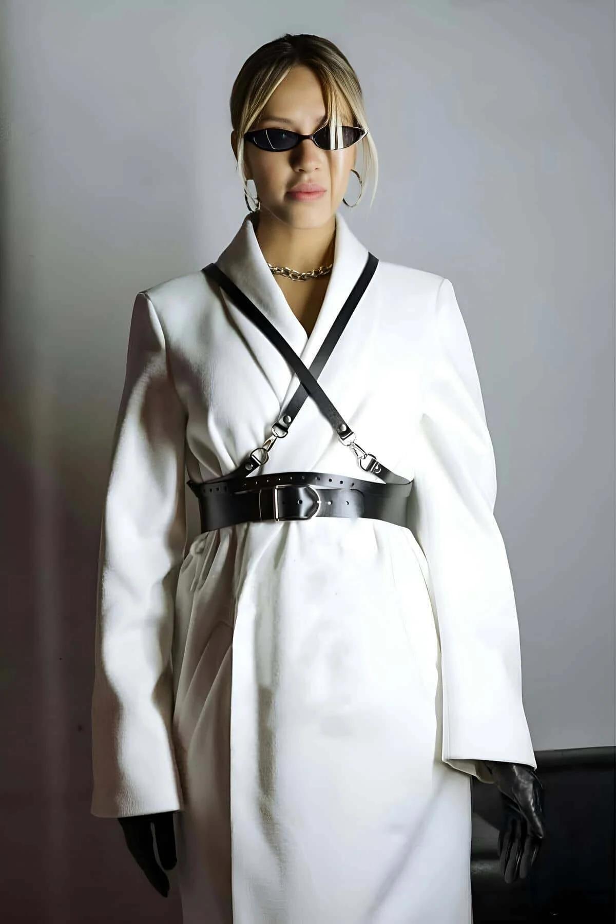 Close-up of silver zinc-alloy rectangular buckle and square sub-buckle on black faux leather harness belt