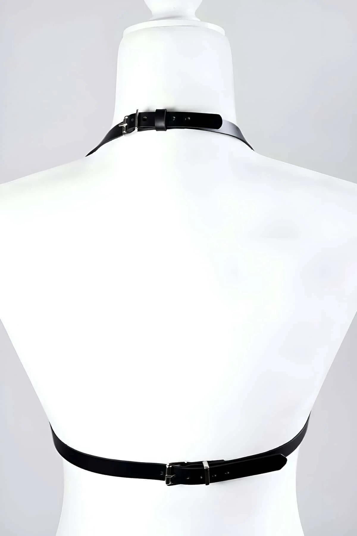 Side angle of structured black faux leather bra harness with silver-tone hardware on smooth matte panels