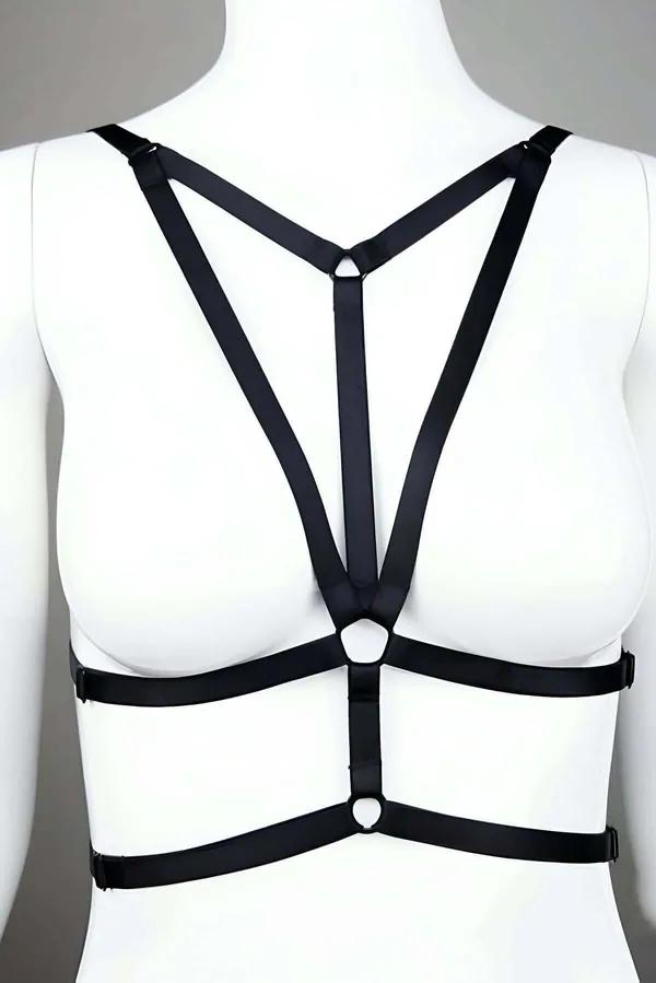 Black strappy chest harness with Y-strap silhouette and dual O-ring accents on white mannequin