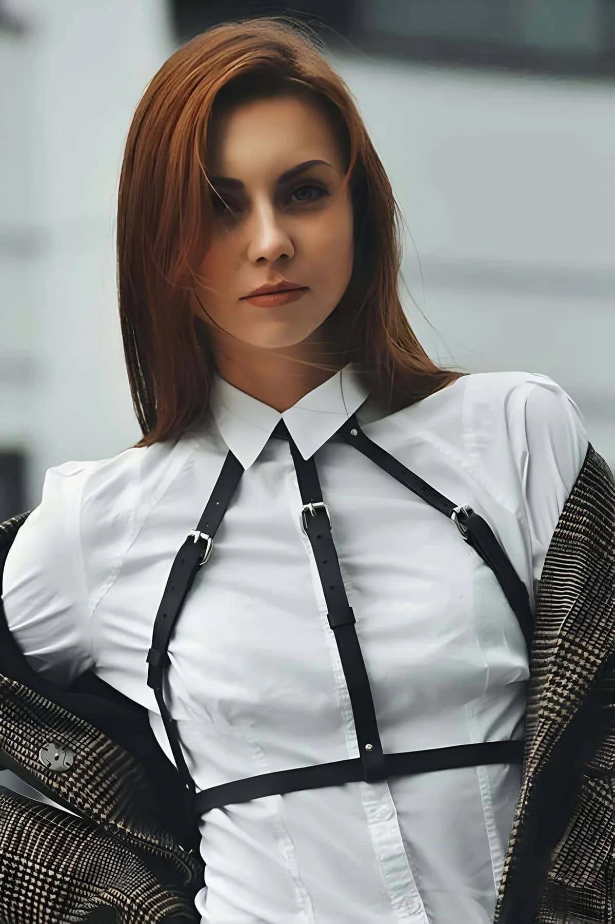 Black vegan leather adjustable strappy chest harness with silver buckles worn over white shirt
