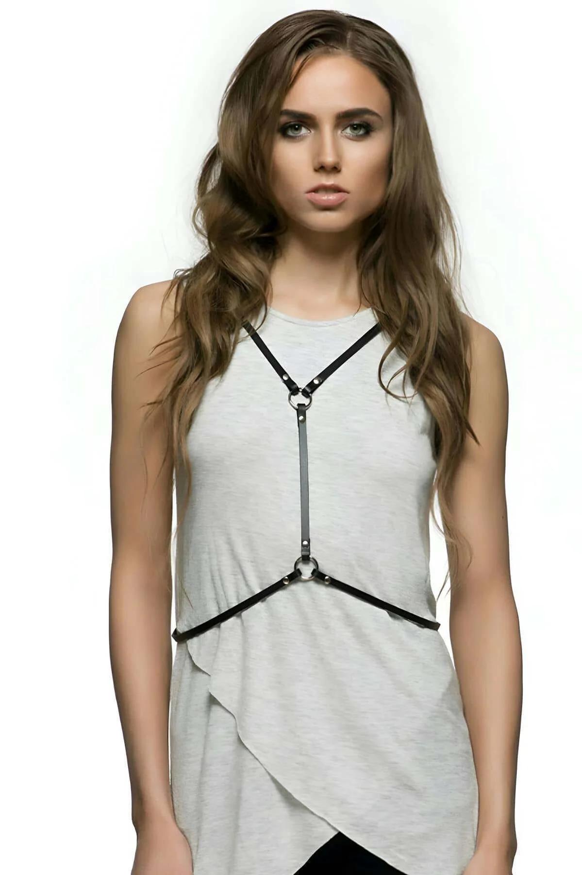 Slim black PU leather harness straps crossing at silver lobster-claw O-ring, close-up back detail