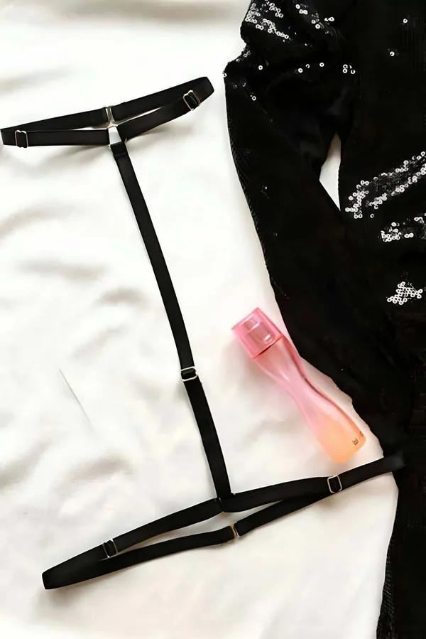 Black adjustable strappy body harness with silver slide adjusters laid flat, geometric cage strap design