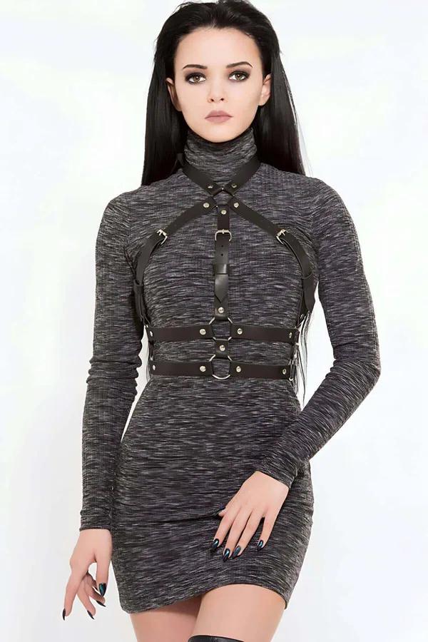 Black faux leather adjustable chest harness with silver O-rings and buckles worn over a grey turtleneck dress