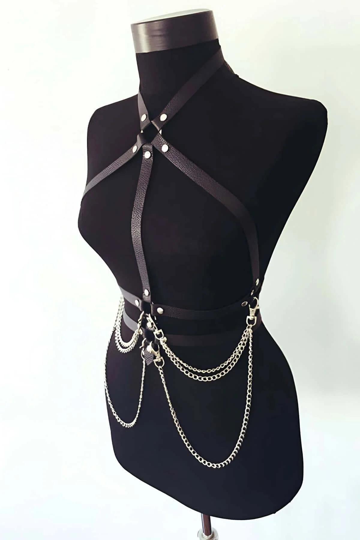 Close-up of gold curb link chains hanging from D-ring hardware on black faux leather waist band