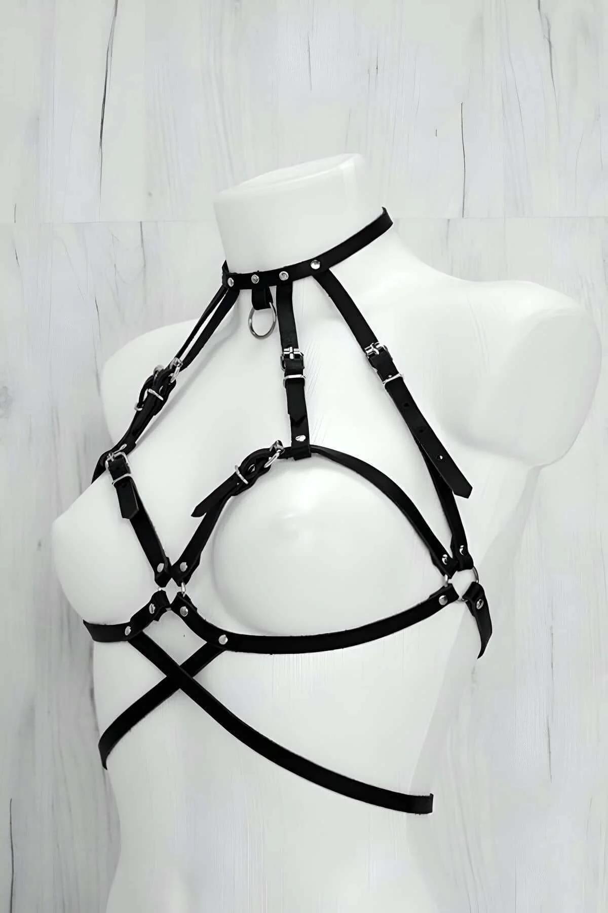 Close-up of silver-tone O-ring buckle hardware on black faux leather harness straps