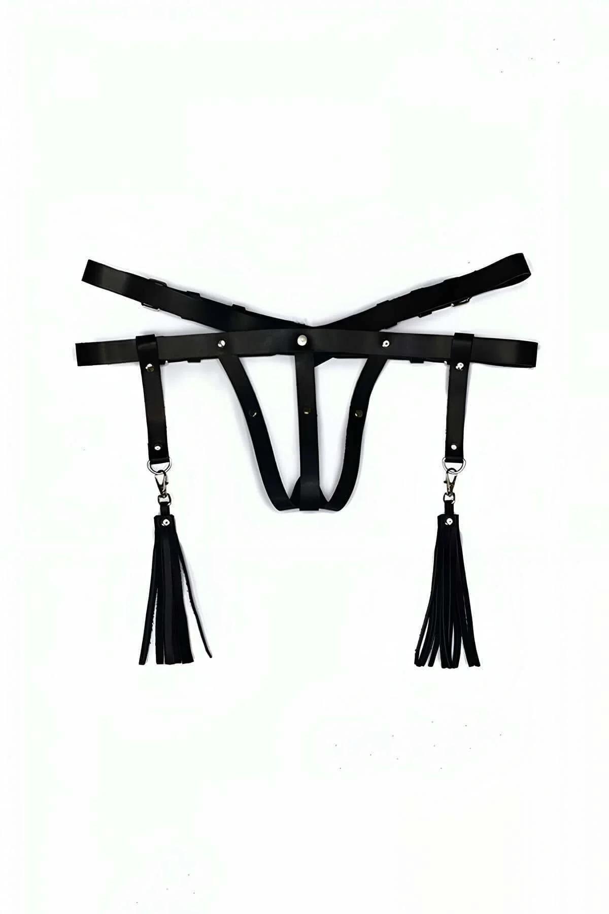 black faux leather thong harness with two detachable fringe tassels clipped to silver D-ring hip straps, flat lay view