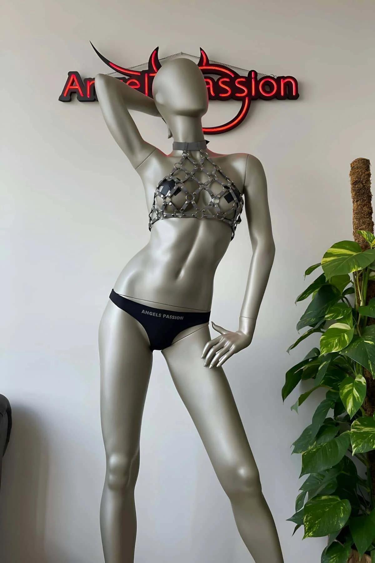 Chainmail halter harness worn over bare skin showing open-link mesh gap pattern against dark background
