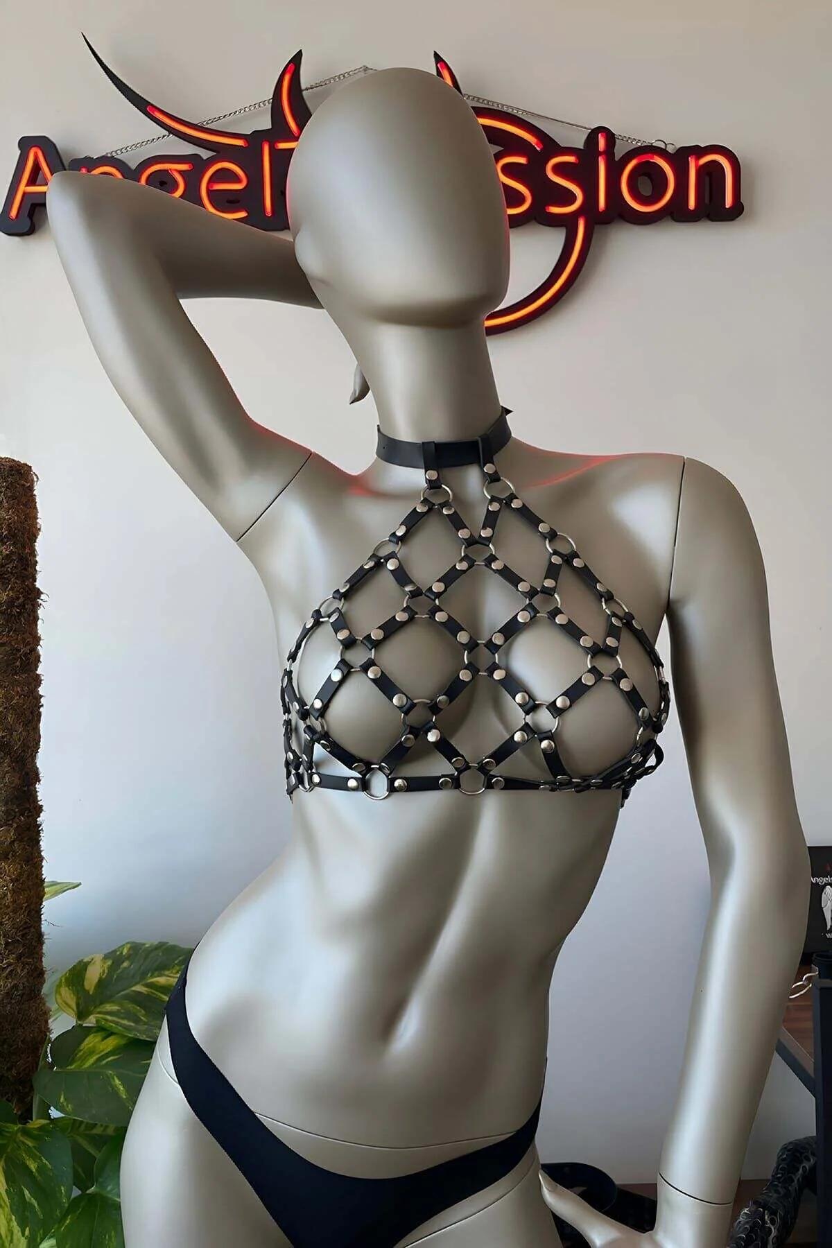 Black cage harness worn over a sheer mesh top showing layered street-style outfit