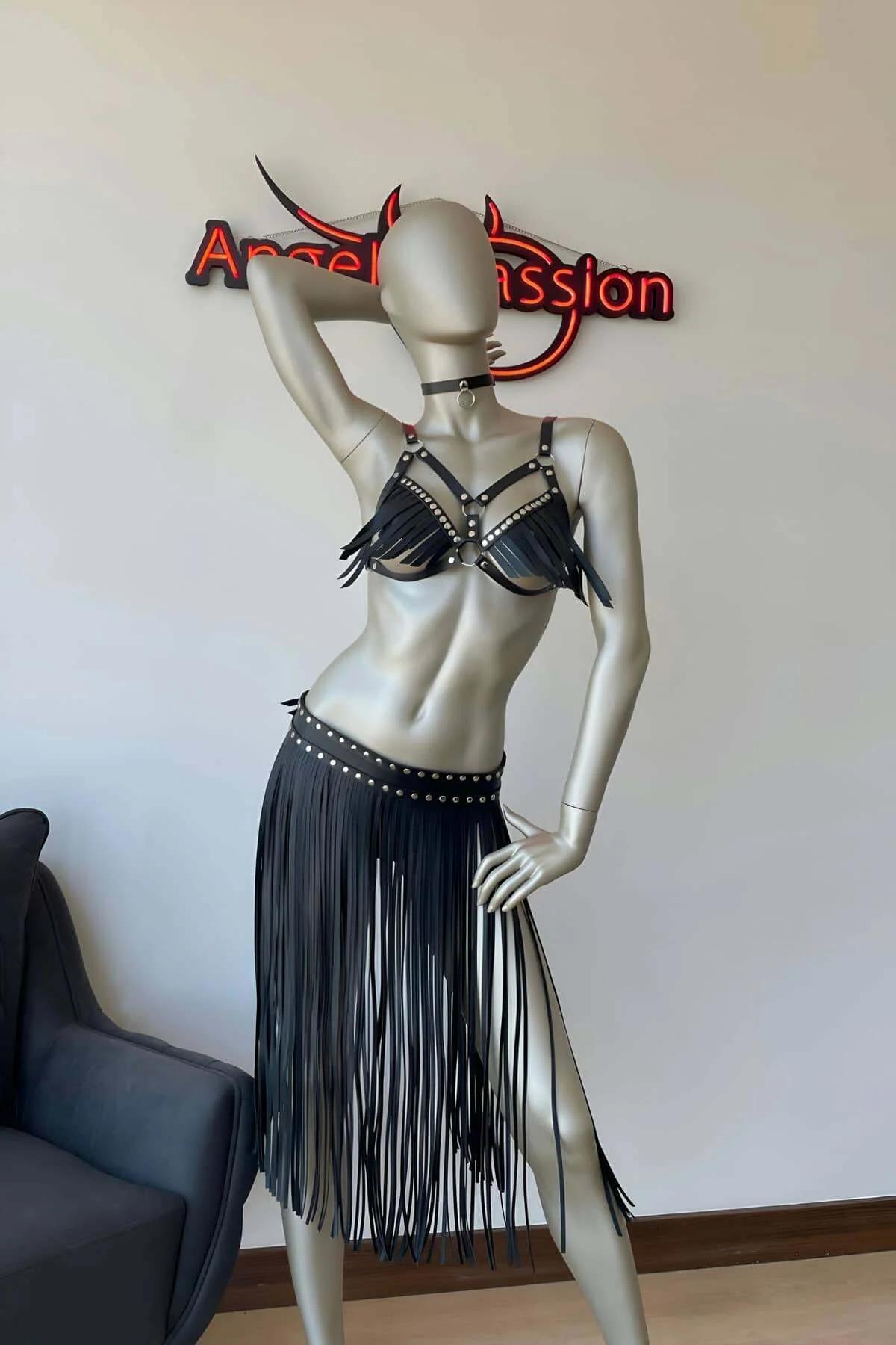 Close-up of black faux leather harness bra cups with fringe strips and silver dome studs on shoulder straps