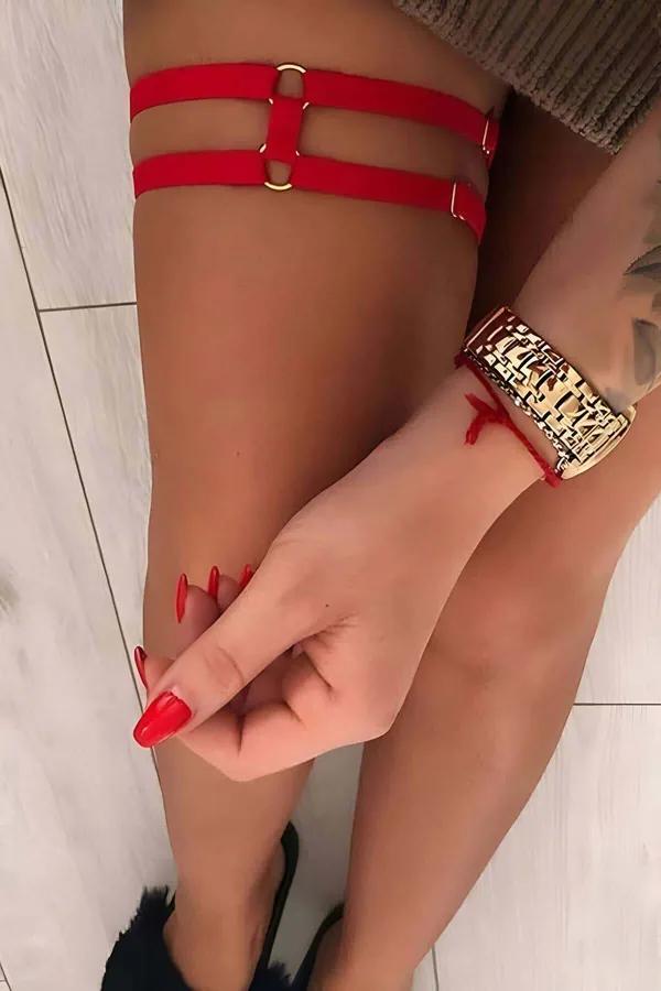 Red elastic double-band thigh harness with gold O-ring connectors worn on upper thigh