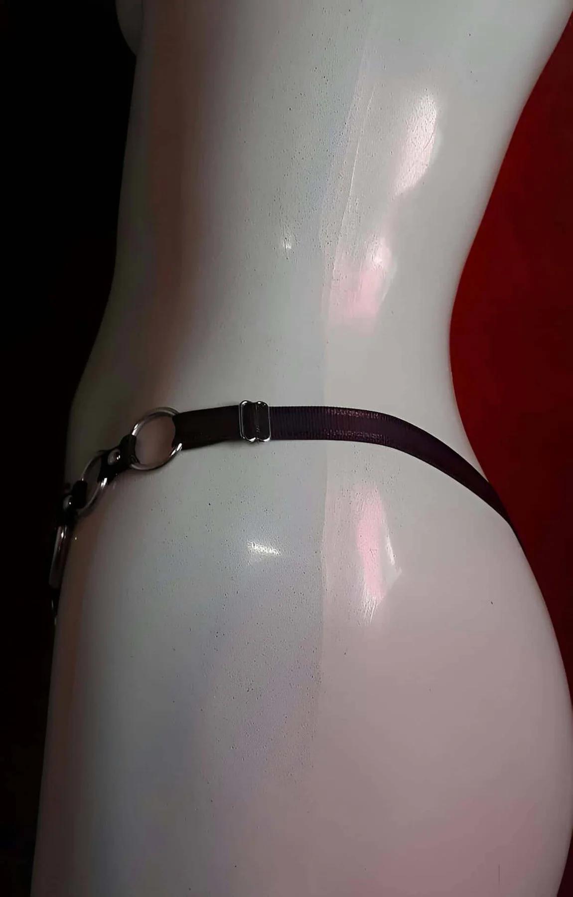 Black faux leather waist and crotch harness flat lay showing geometric strap configuration
