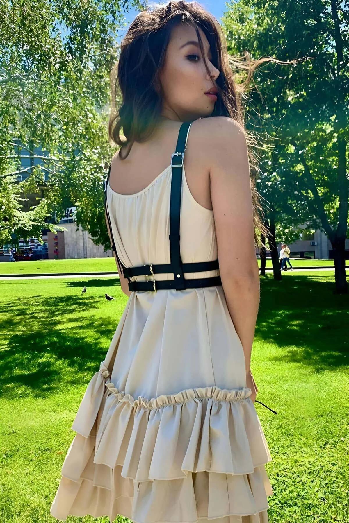 Front view of black strappy chest harness with four adjustable slider buckles and gold hardware