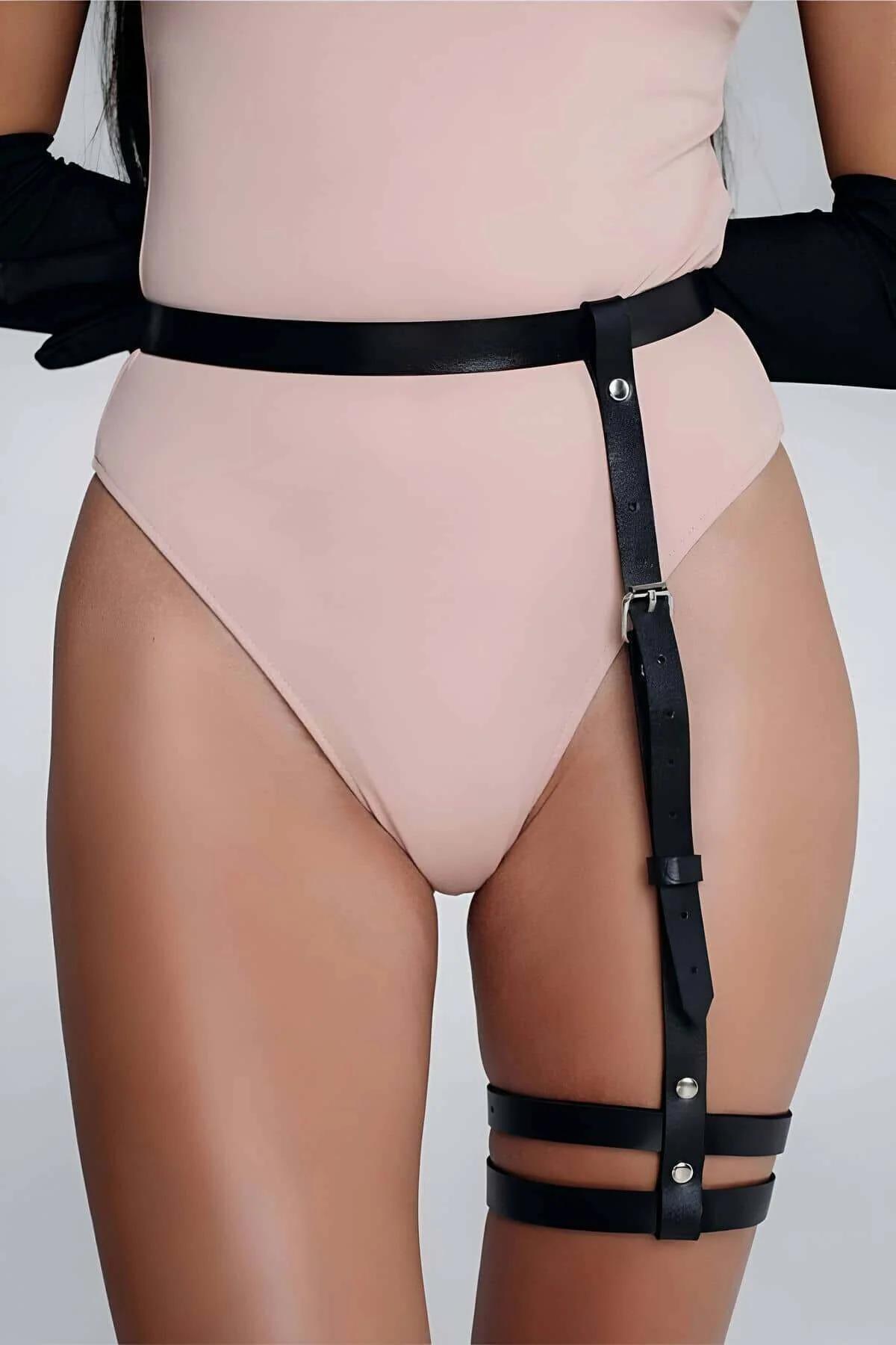 Black adjustable thigh garter belt worn over bare skin showing strap placement 5–8 cm below hip crease