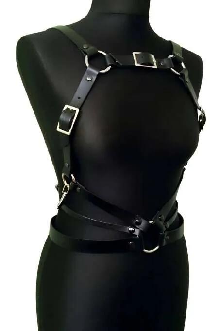 close-up of silver O-ring and square buckle on black faux leather chest harness strap