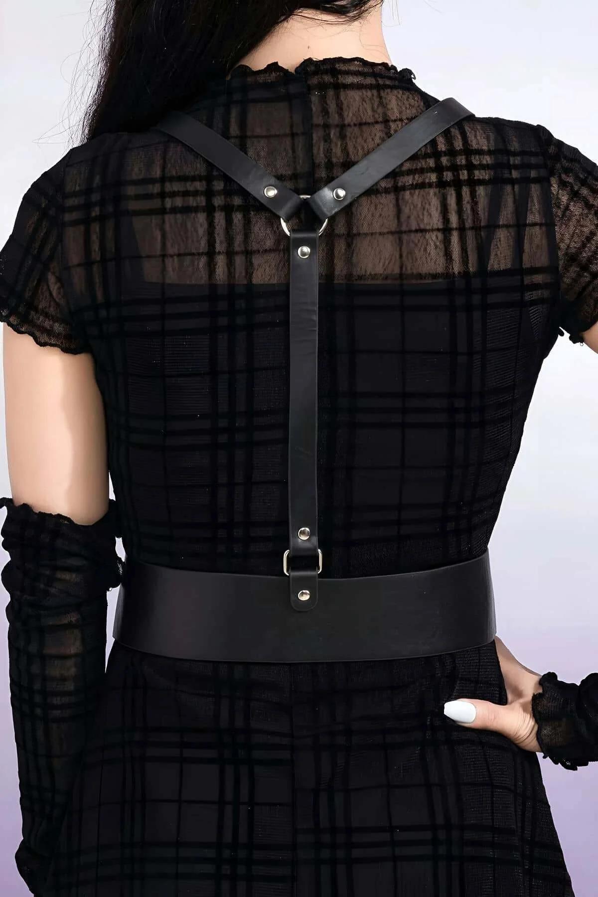 Black faux leather harness layered over sheer long-sleeve top showing structured silhouette