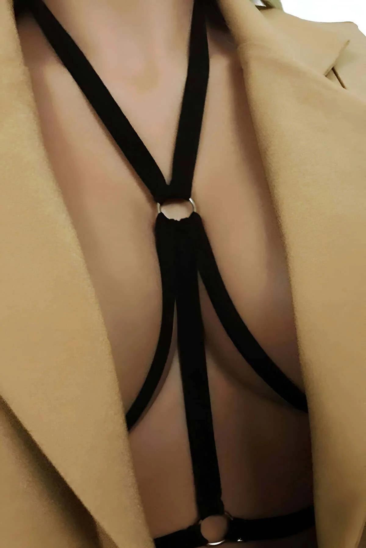 Black elastic O-ring neck strap body harness with silver hardware worn over camel coat, Y-shaped strap layout