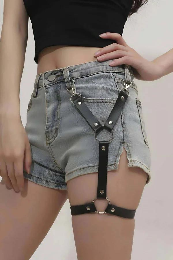 Black faux leather single leg garter harness with belt loop clips and silver O-rings worn over light wash denim shorts