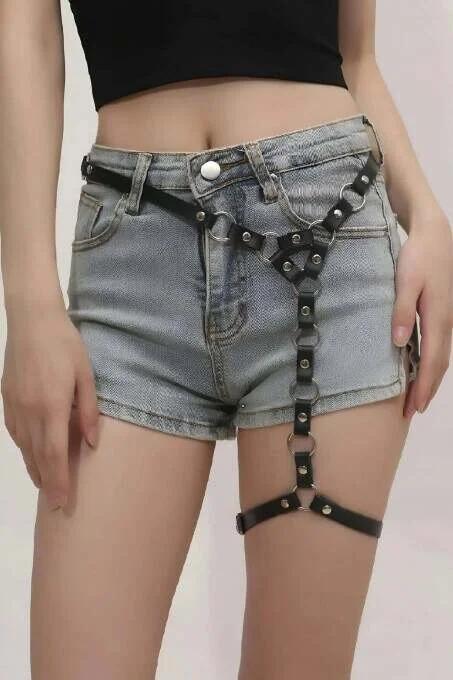 Close-up of silver O-ring and rivet detail on black faux leather single leg harness straps