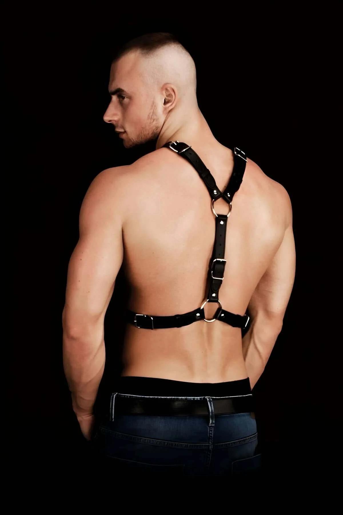Close-up of silver dome studs on black faux leather vertical chest strap with O-ring detail