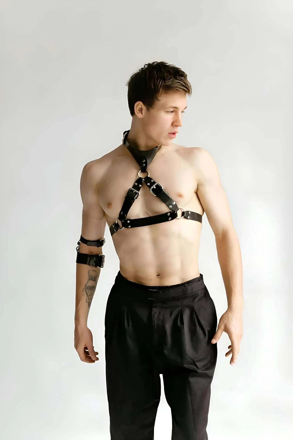 Black faux leather chest harness with X-cross straps, silver D-rings, matching collar and armbands on male model