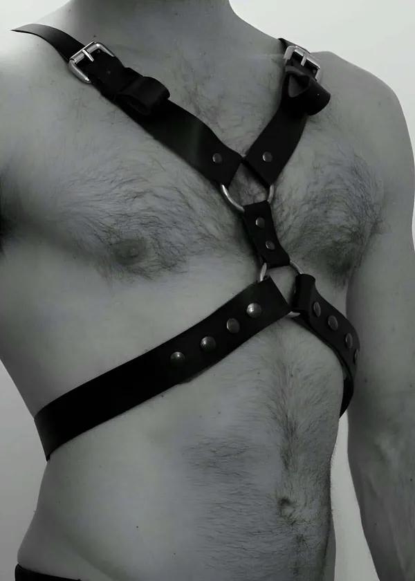 black faux leather chest body harness with silver buckles and center O-ring worn on male torso