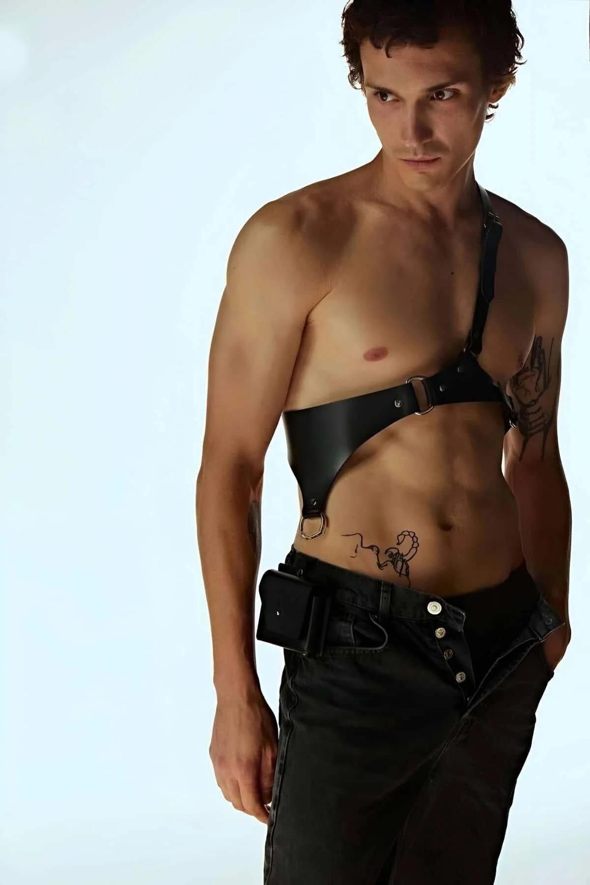 black faux leather body harness worn over bare chest showing diagonal single-shoulder construction