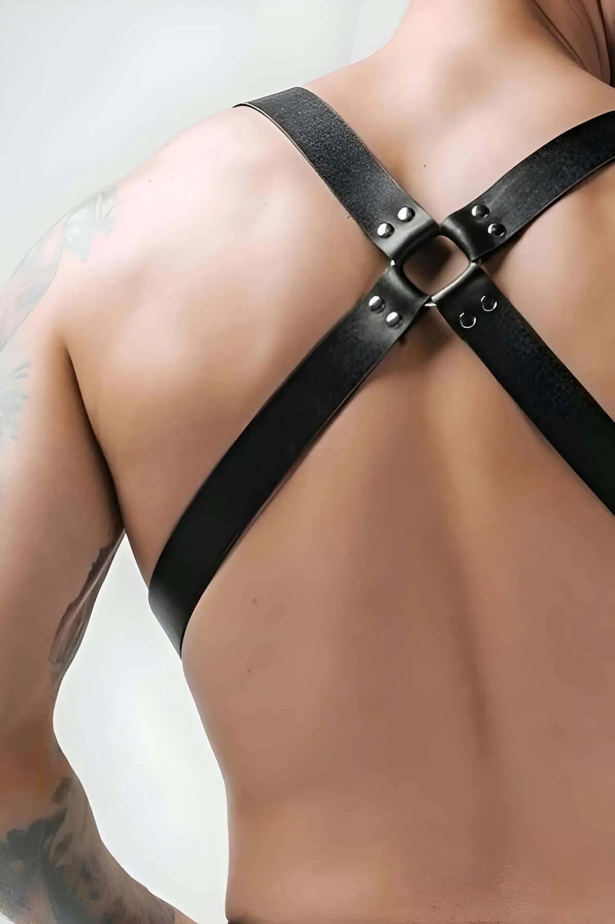 Close-up of silver D-ring and swivel snap hook hardware on black faux leather chest harness