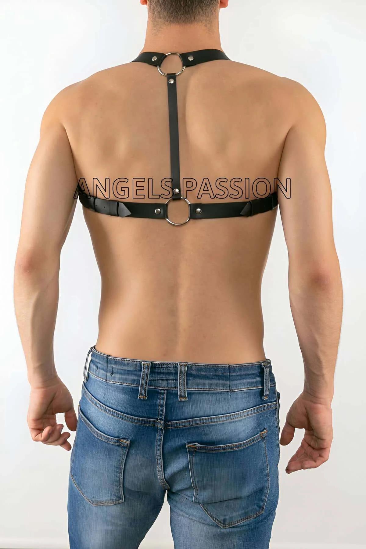 Close-up of silver O-ring and rectangular buckle hardware on black faux leather chest harness