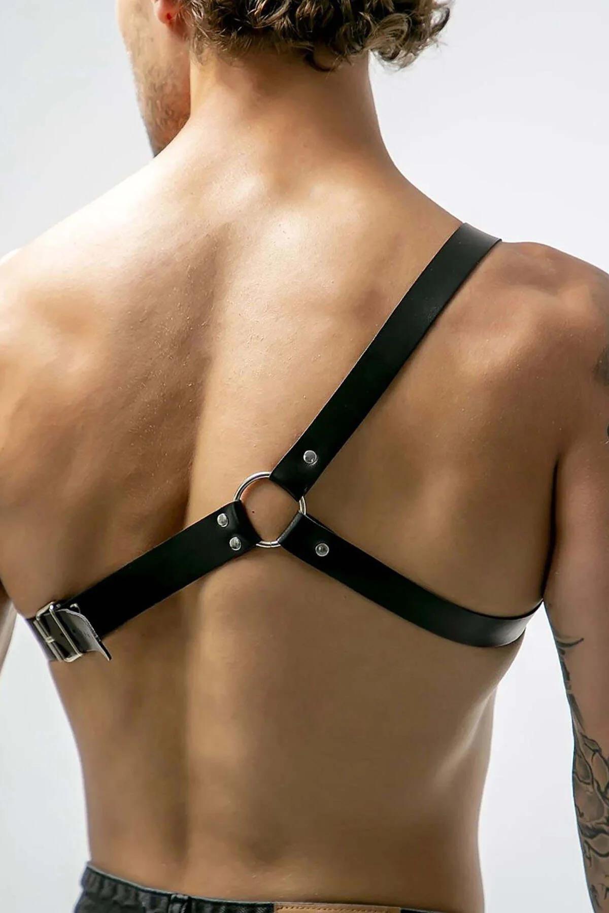 close-up of silver O-ring and rectangular buckle on black faux leather chest harness
