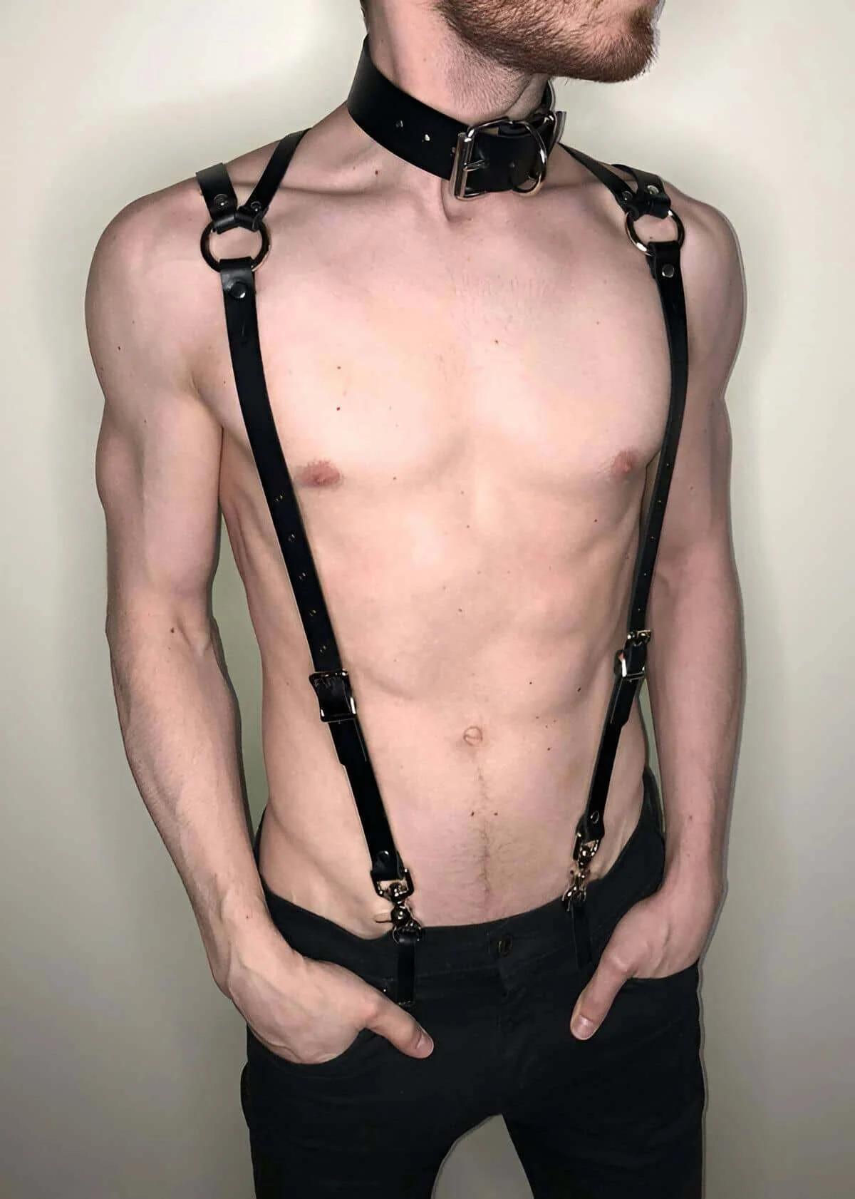 Close-up of silver O-ring hardware at upper back strap intersection on black faux leather harness