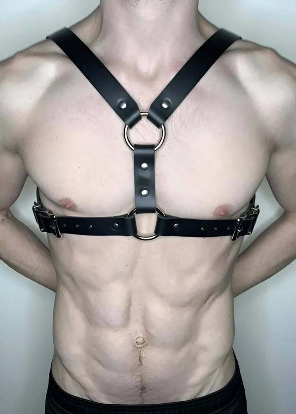black faux leather chest harness with double silver O-rings and adjustable buckle straps worn on male torso
