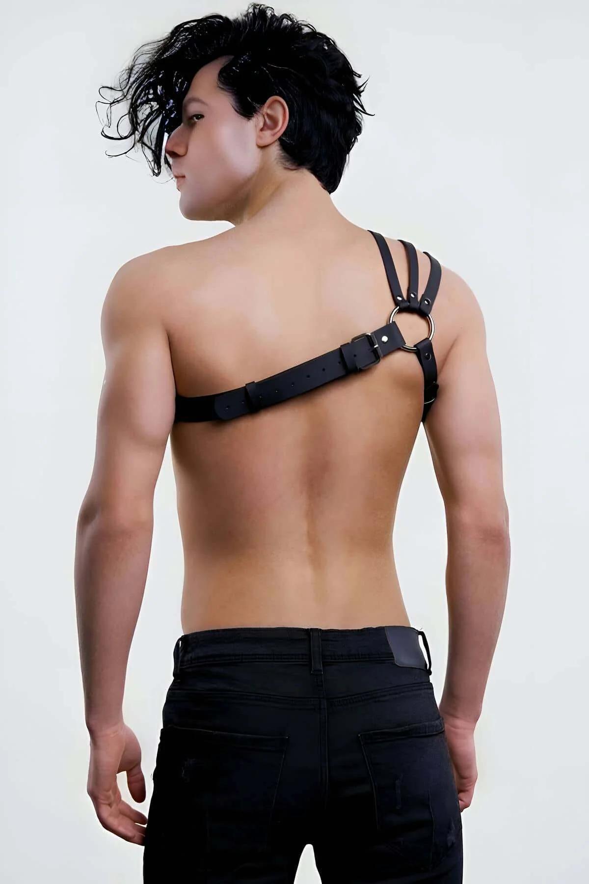 Close-up of silver-tone O-ring center detail on black faux leather asymmetrical chest harness