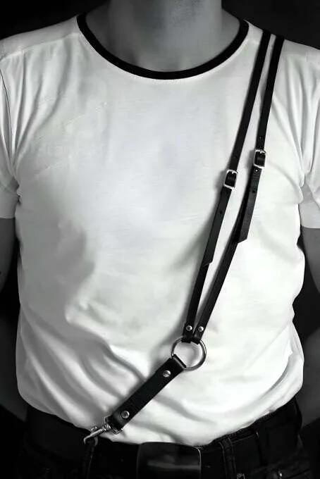 black faux leather chest harness with silver O-ring worn over white t-shirt diagonal strap adjustable mens