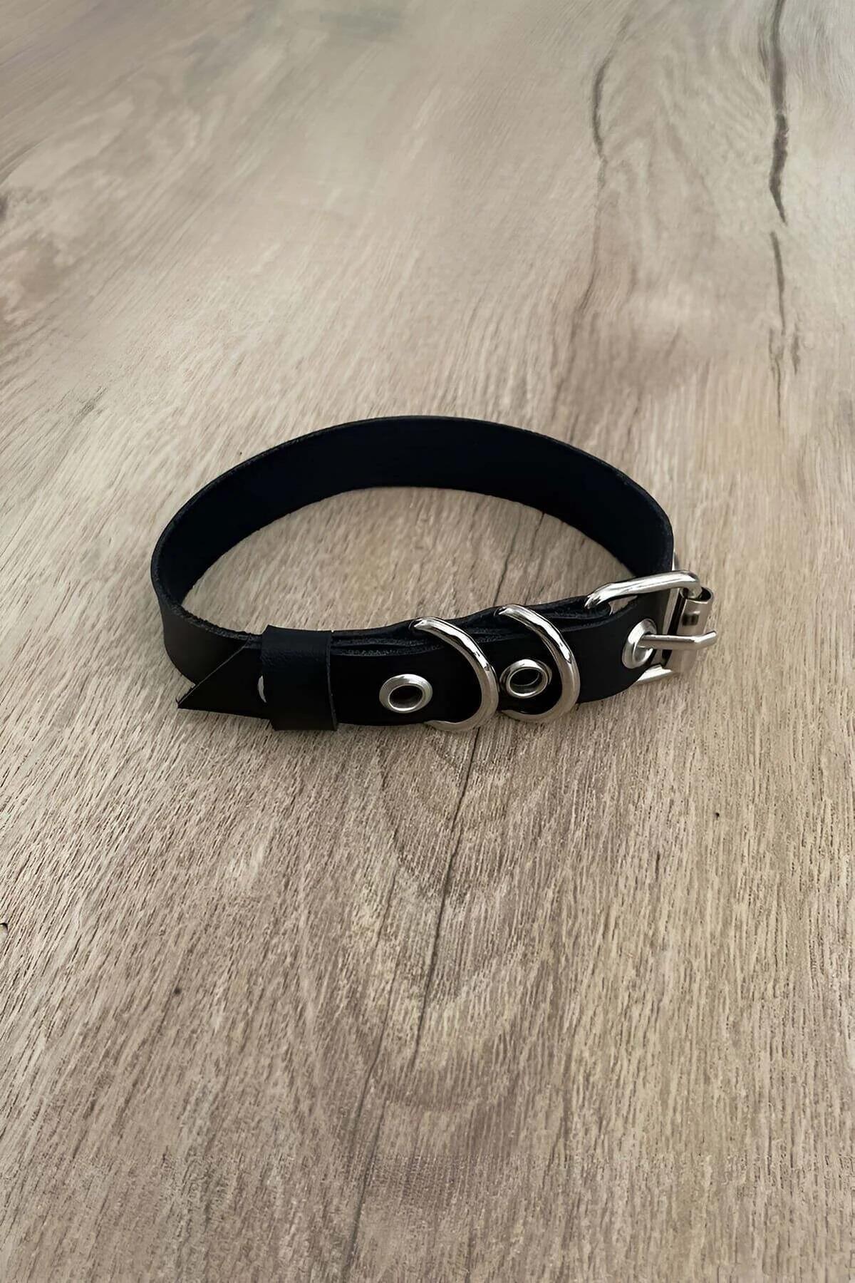 Close-up of dual silver D-rings riveted onto narrow black PU vegan leather strap