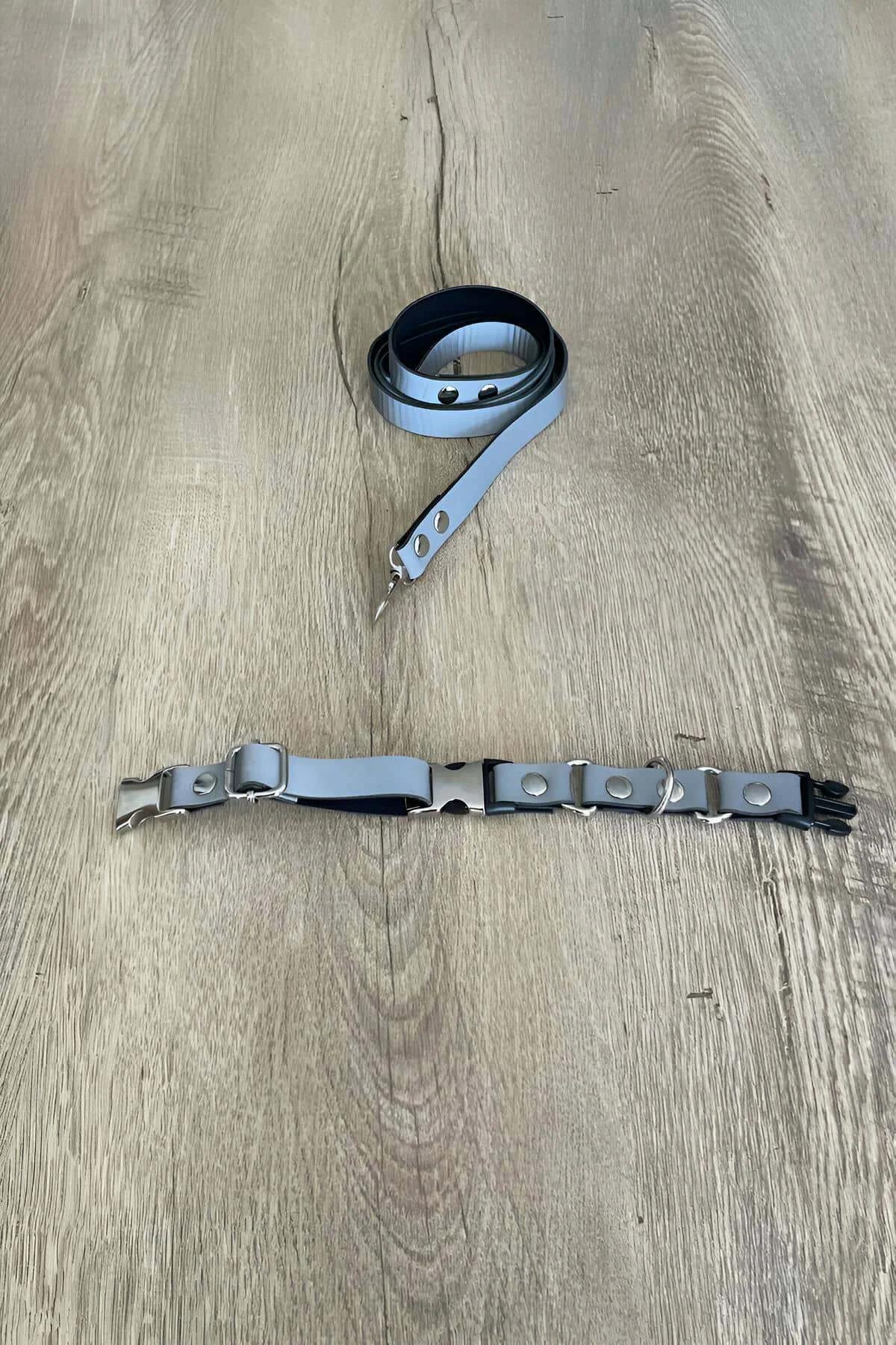 Close-up of silver D-ring and snap-rivet hardware on grey PU leather harness straps