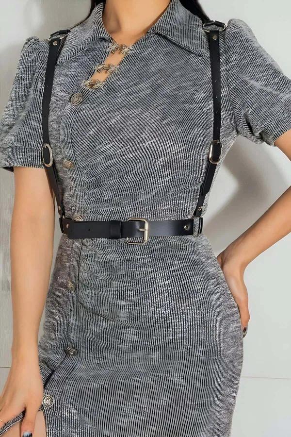 black faux leather adjustable body harness belt with silver O-rings worn over gray tweed dress