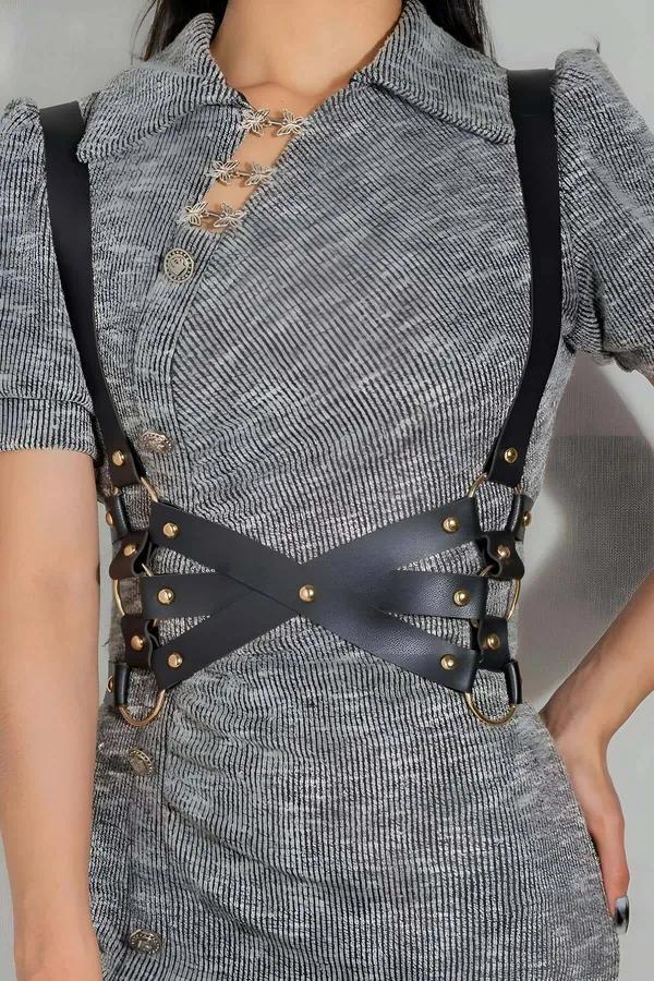 black faux leather X-strap body harness with gold O-ring hardware worn over gray knit dress