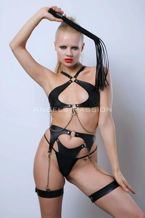 Black faux leather full body harness with open-cup chest, gold-tone O-rings, chain links, and thigh garter straps on model