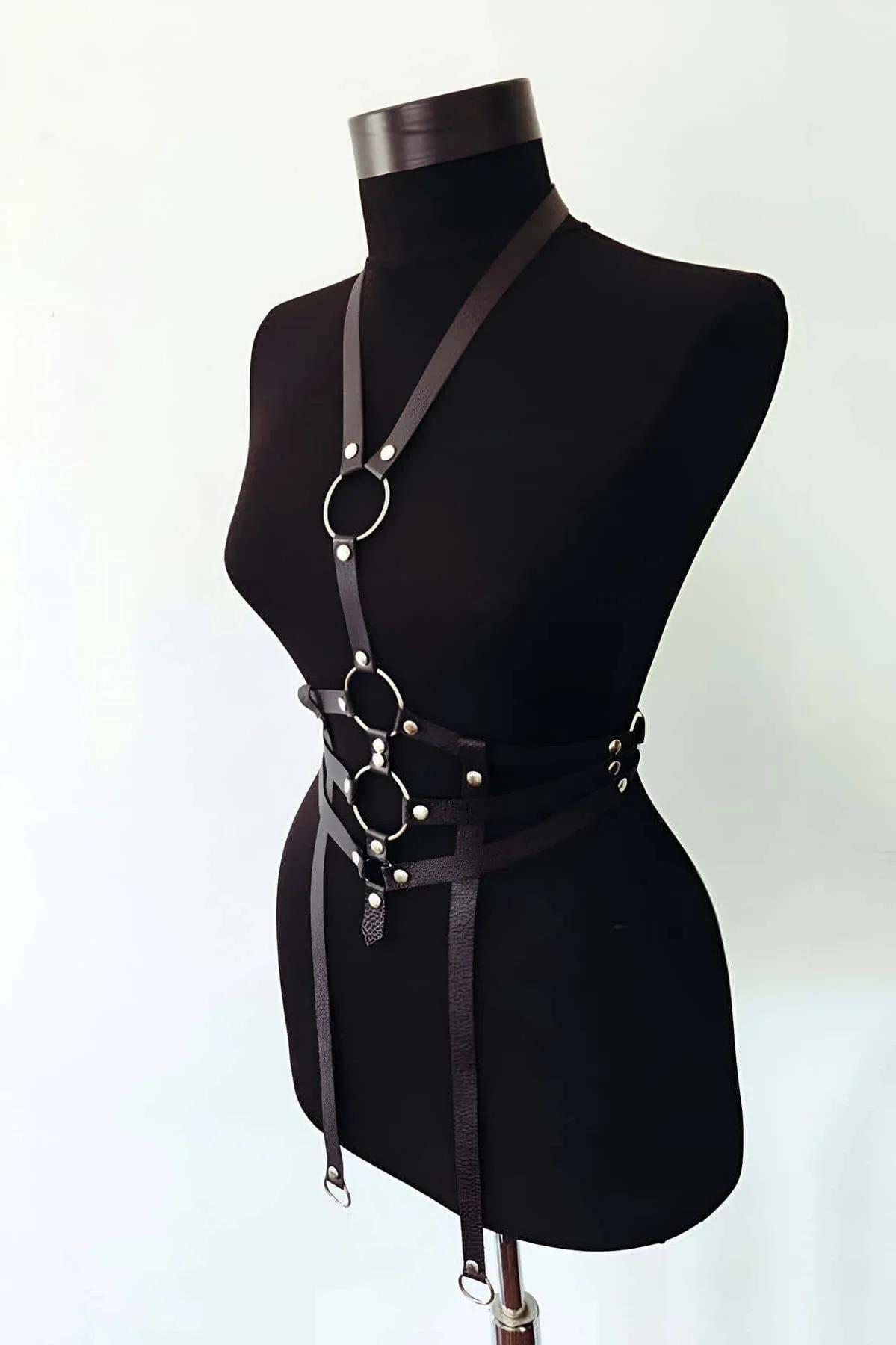 Black faux leather triple O-ring body harness with diagonal shoulder strap, silver hardware, and detachable chain accent on m
