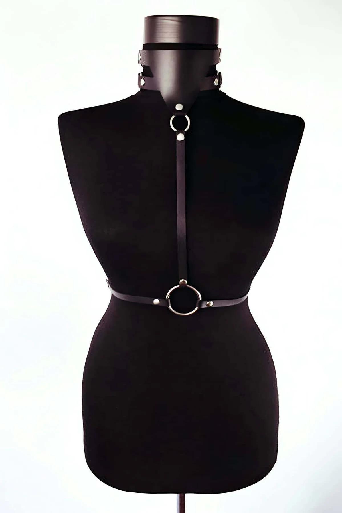 Black faux leather chest harness with silver O-rings and matching choker collar on mannequin, front view
