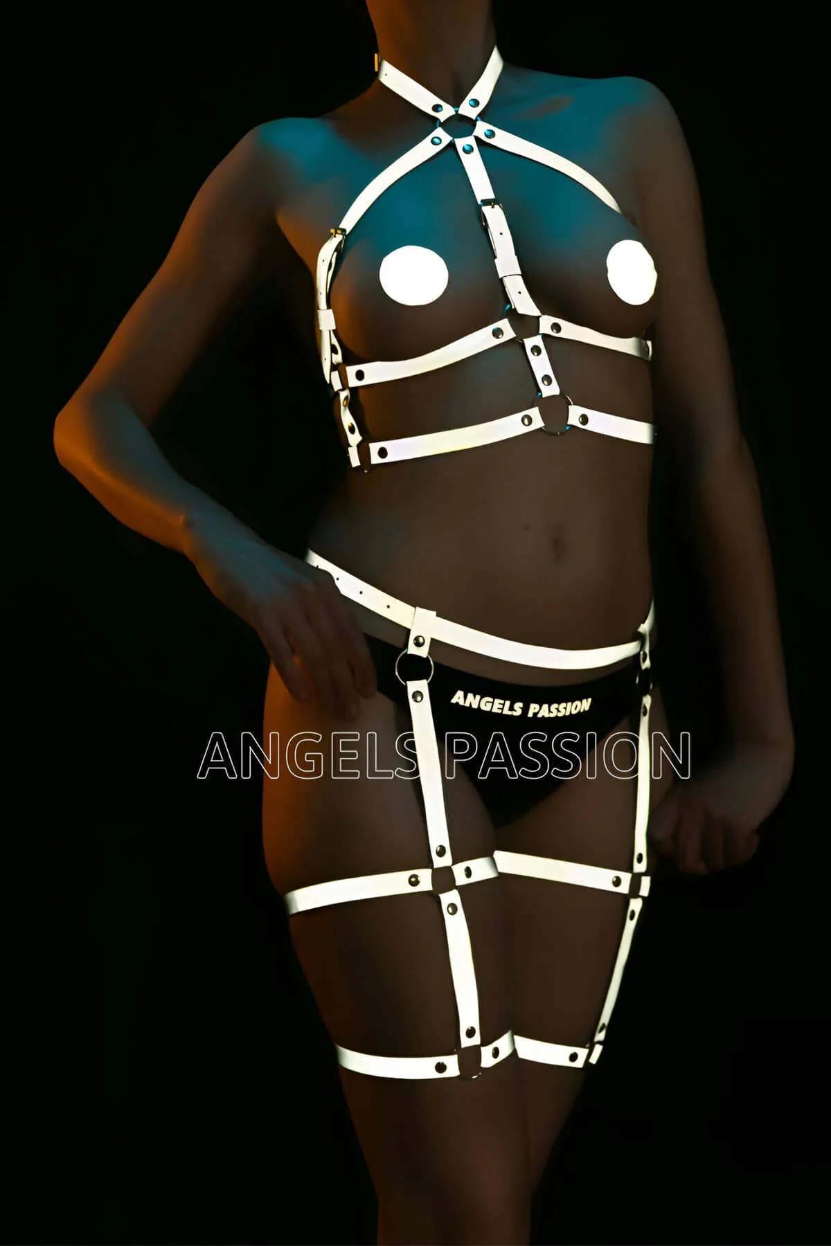Reflective full body harness white straps glowing under UV light with silver O-rings and thigh cage panels