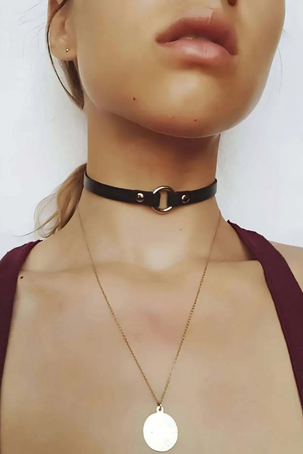 Black faux leather choker with silver O-ring rivet detail worn close to the throat, slim 1 cm band