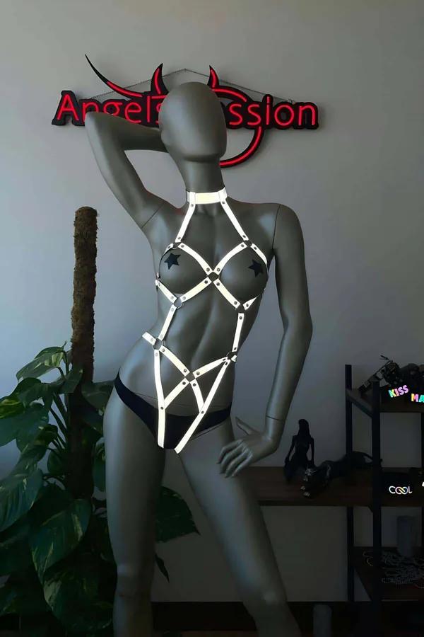White reflective full body harness with star-shaped silver hardware on grey mannequin, geometric cage strap design from neck